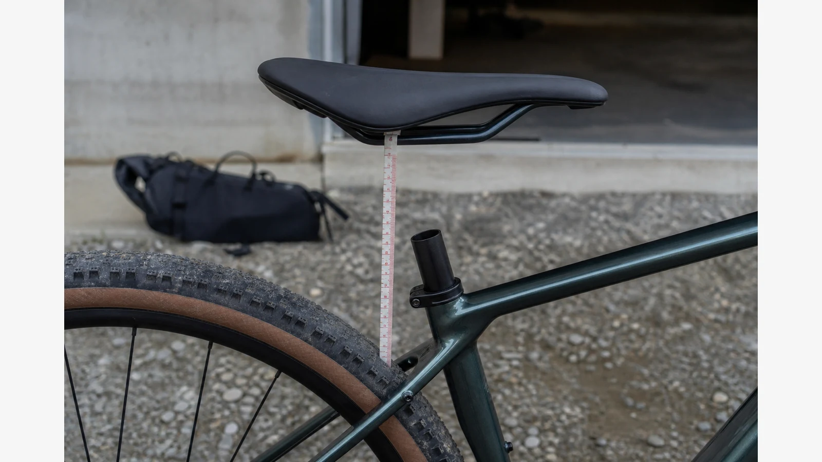 Cyclist measuring saddle-to-tyre clearance on a gravel bike with the dropper fully down