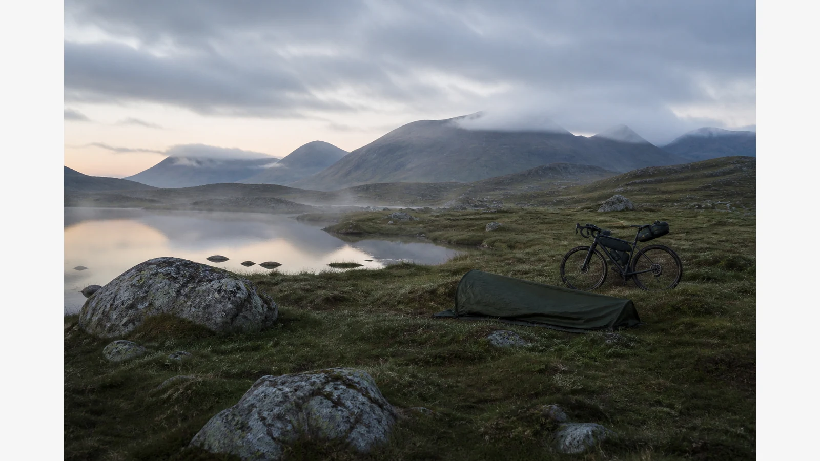 Lightweight bike camping setup on open Scottish ground with a compact rear seat pack